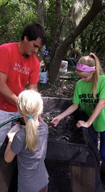 Scott Dawson in the field showing his daughters how to do archaeology.